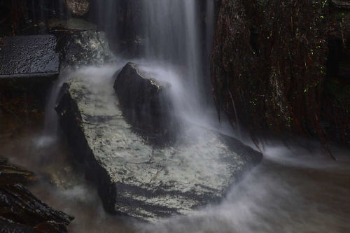 photo de cascade sur une grosse pierre en pose longue