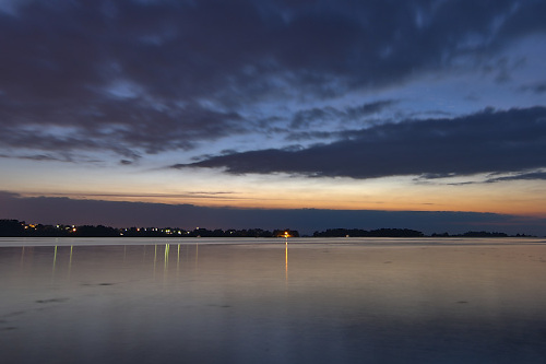 photo de crépuscule sur la mer et les reflets d'une ville au loin