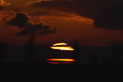 photo du soleil levant masqué par des nuages