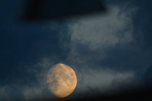 photo de la lune qui passe sous un lampadaire